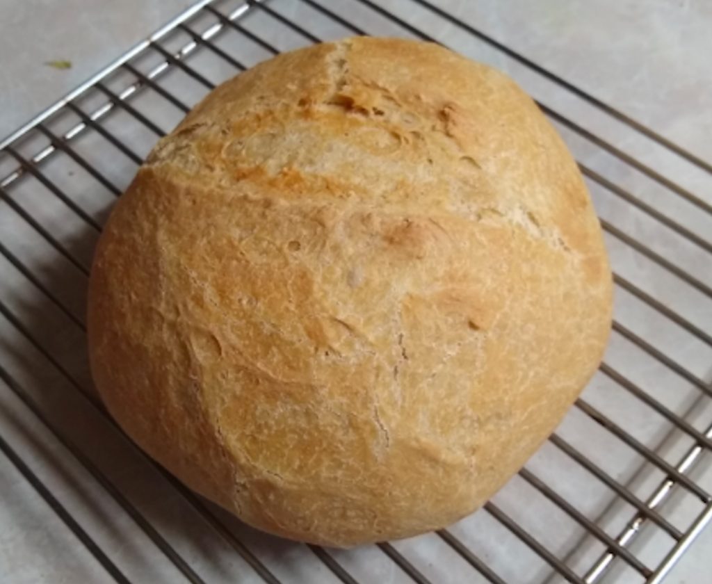 A loaf of bread sits on a cooling rack.